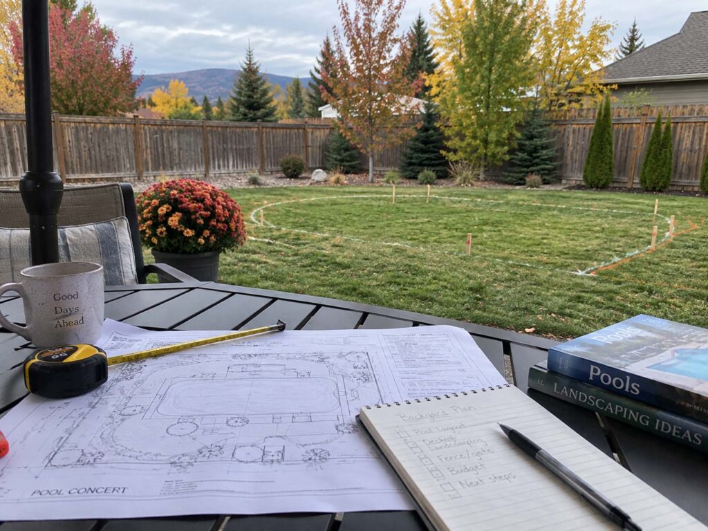 Backyard pool planning table with blueprints and marked lawn in Spokane and Coeur d'Alene